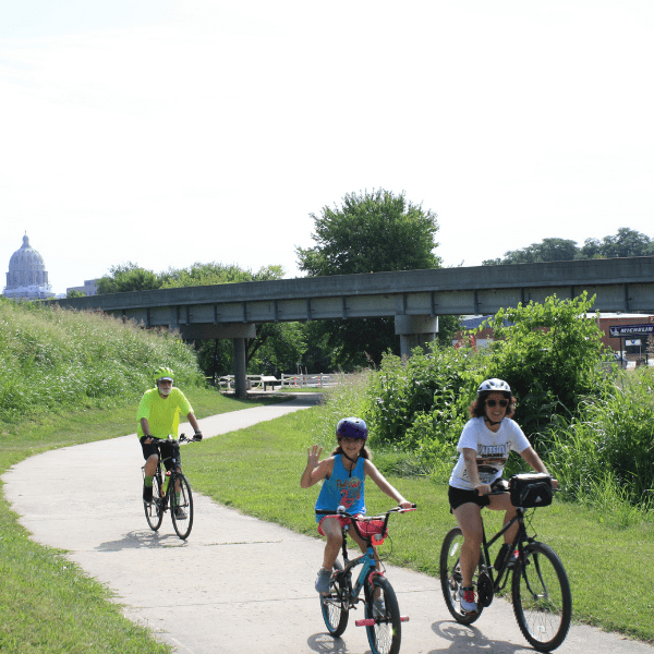 Family of three on a community bike ride with capitol building in background.