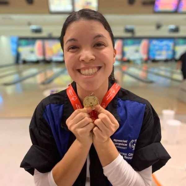 Young woman showing off her adaptive bowling medal.