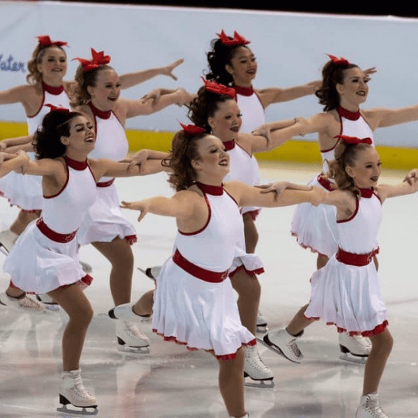 Capital Classics synchronized skating team performing a routine in white and red costumes. 